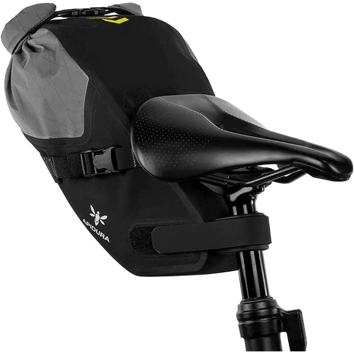 Apidura Dropper Post Adapter on a bike bar with a bag strapped in on a white background