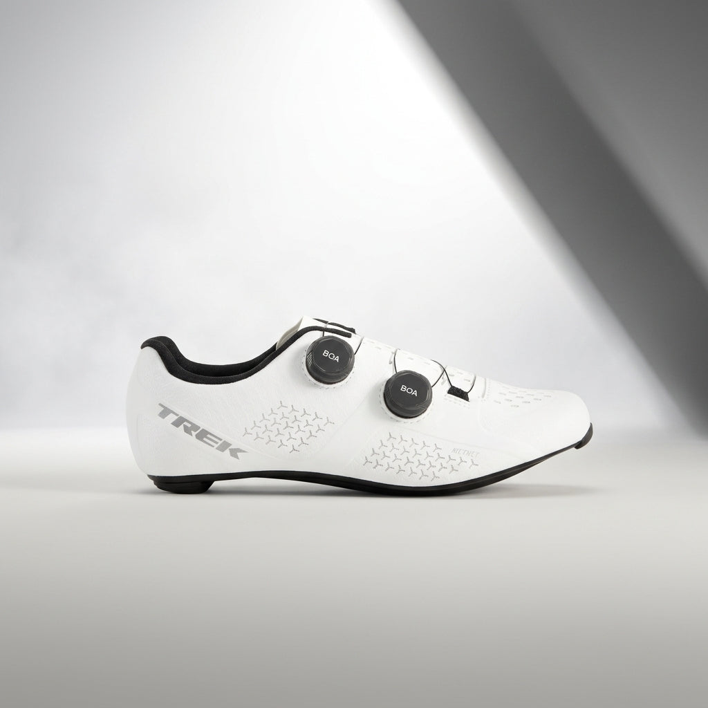 Two white Fiznik cycling shoes placed on top of each other with a blurred background