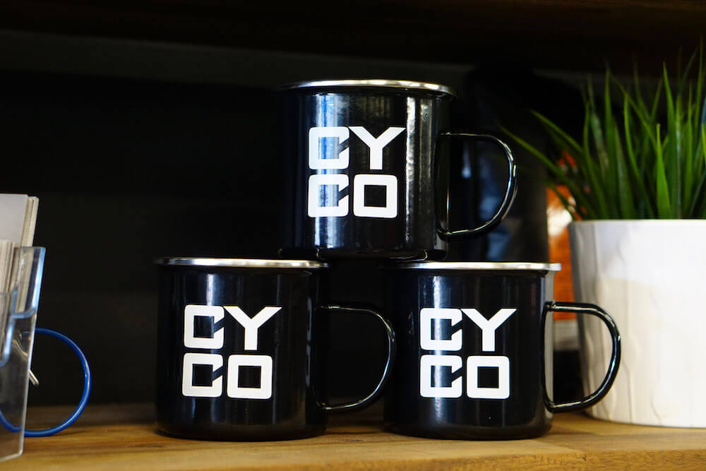 Three cyco cups stacked on each other on a wooden bench with a black background